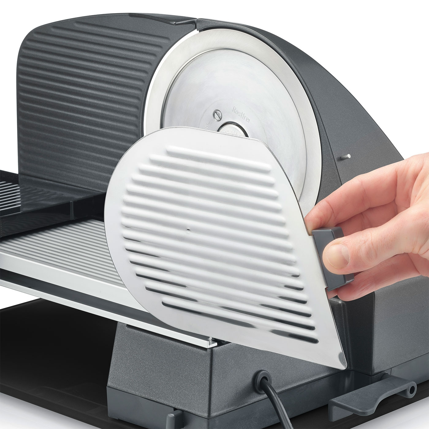 Fleischschneider mit Schutzvorrichtung und Hand, die sie bedient.