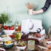Tisch mit Essen, Getränken und einer Person, die etwas hält.