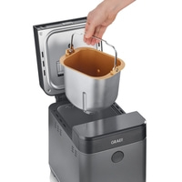 Bread maker with removable container, hand holding handle, open lid