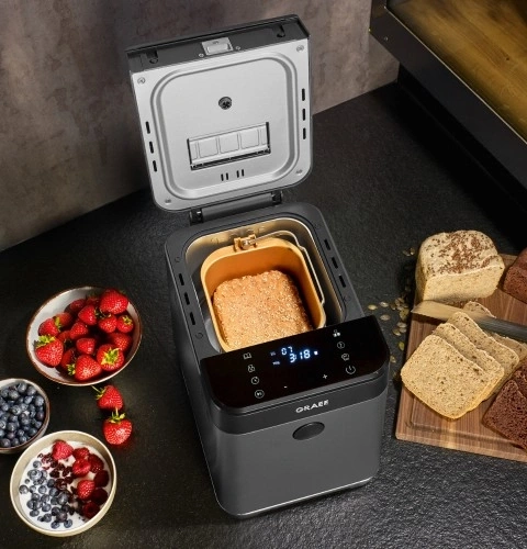 Bread maker with bread, fruits and bread on a cutting board.