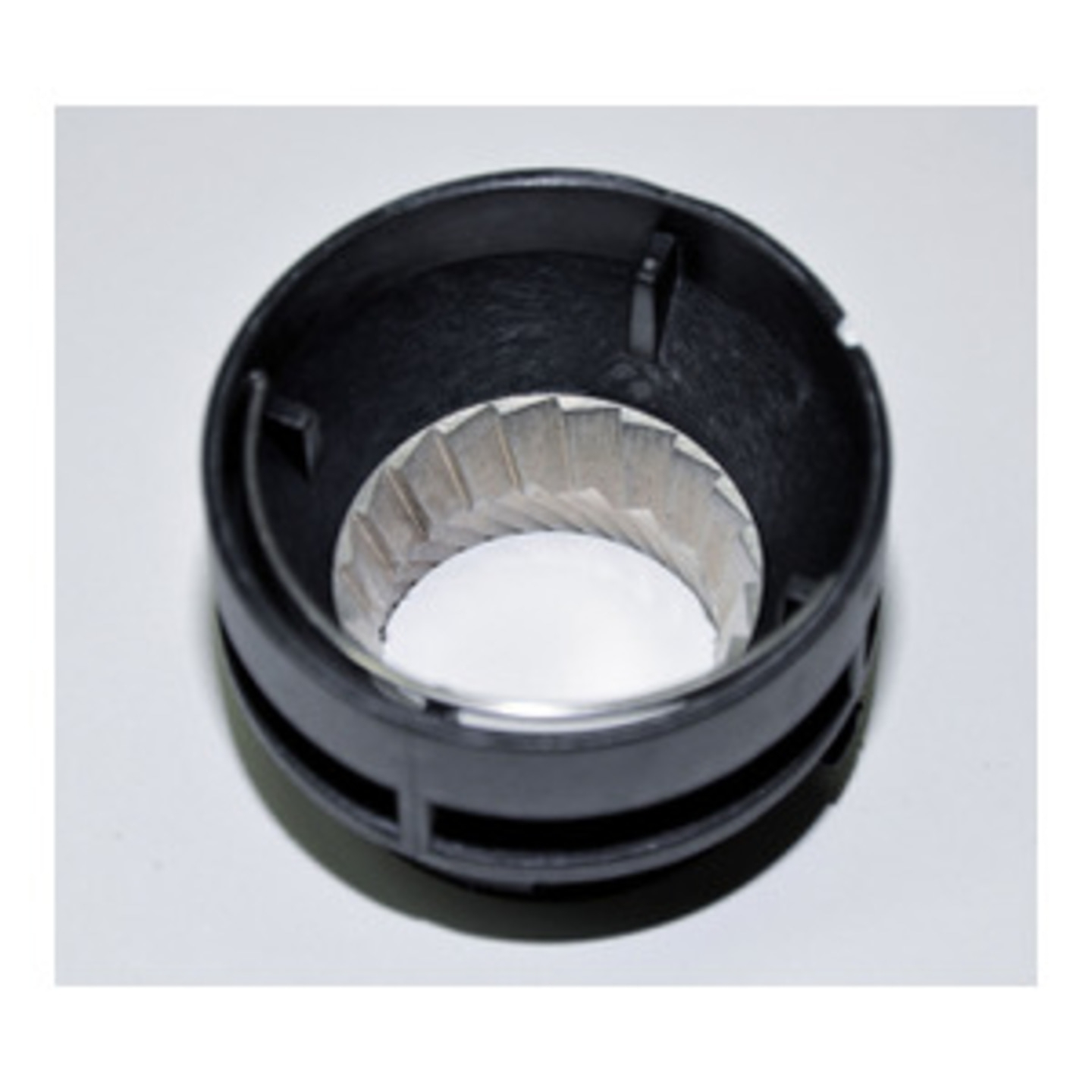 Schwarzer Kunststoffring mit Metallteil in der Mitte, von oben gesehen.