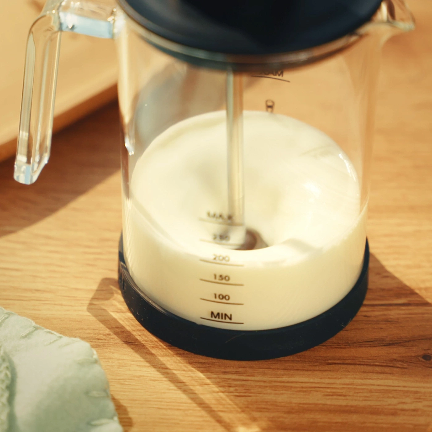 Milchaufschäumer mit Milch auf einem Holztisch