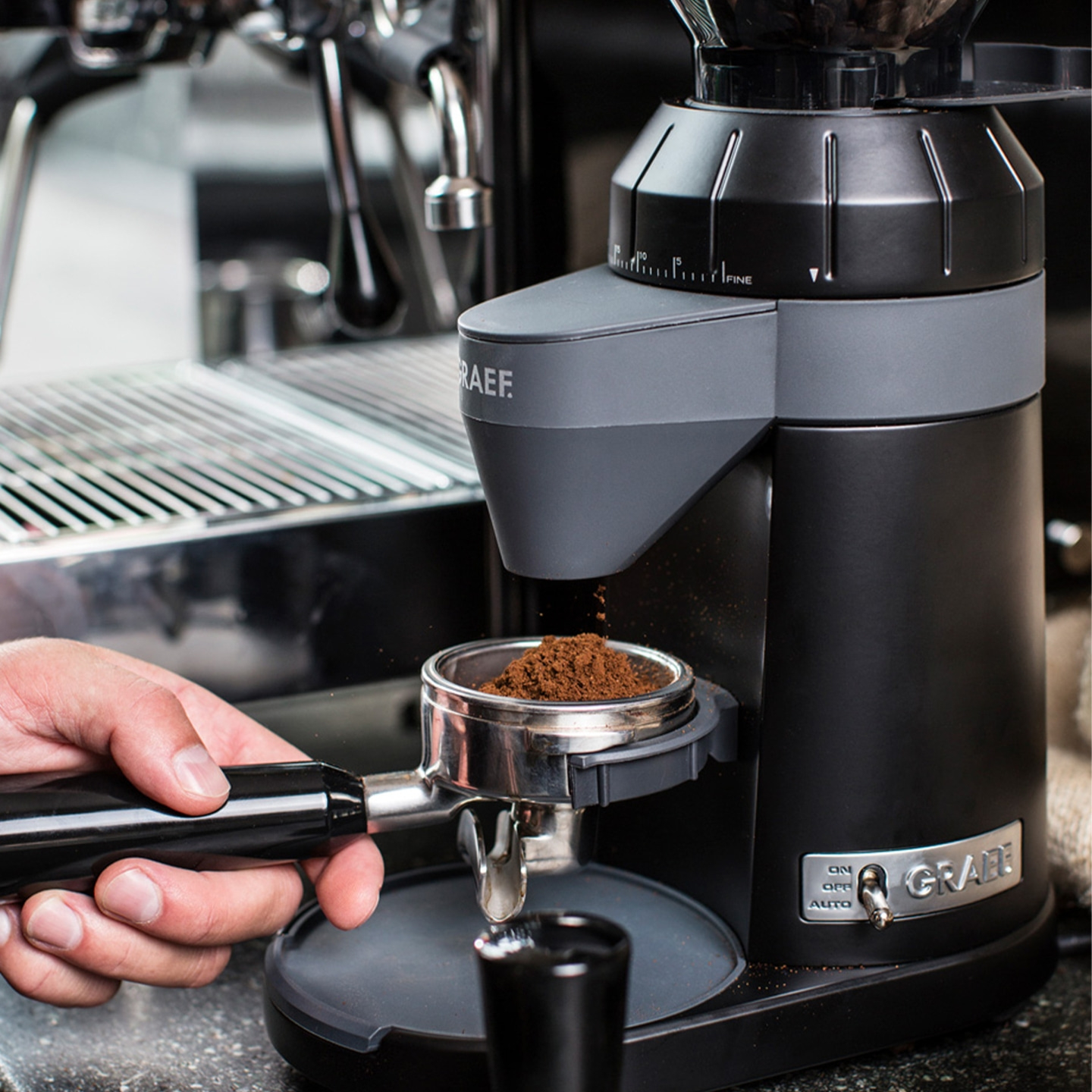 Kaffeemühle mahlt Kaffeepulver in einen Siebträger, nahaufnahme, schwarz.