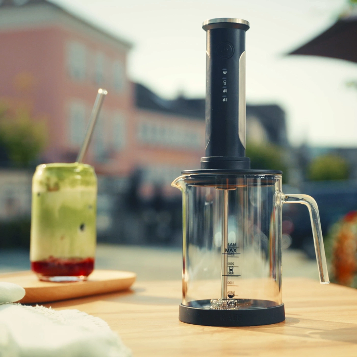 Kaffeemaschine mit Glasbehälter und einem grünen Getränk daneben.