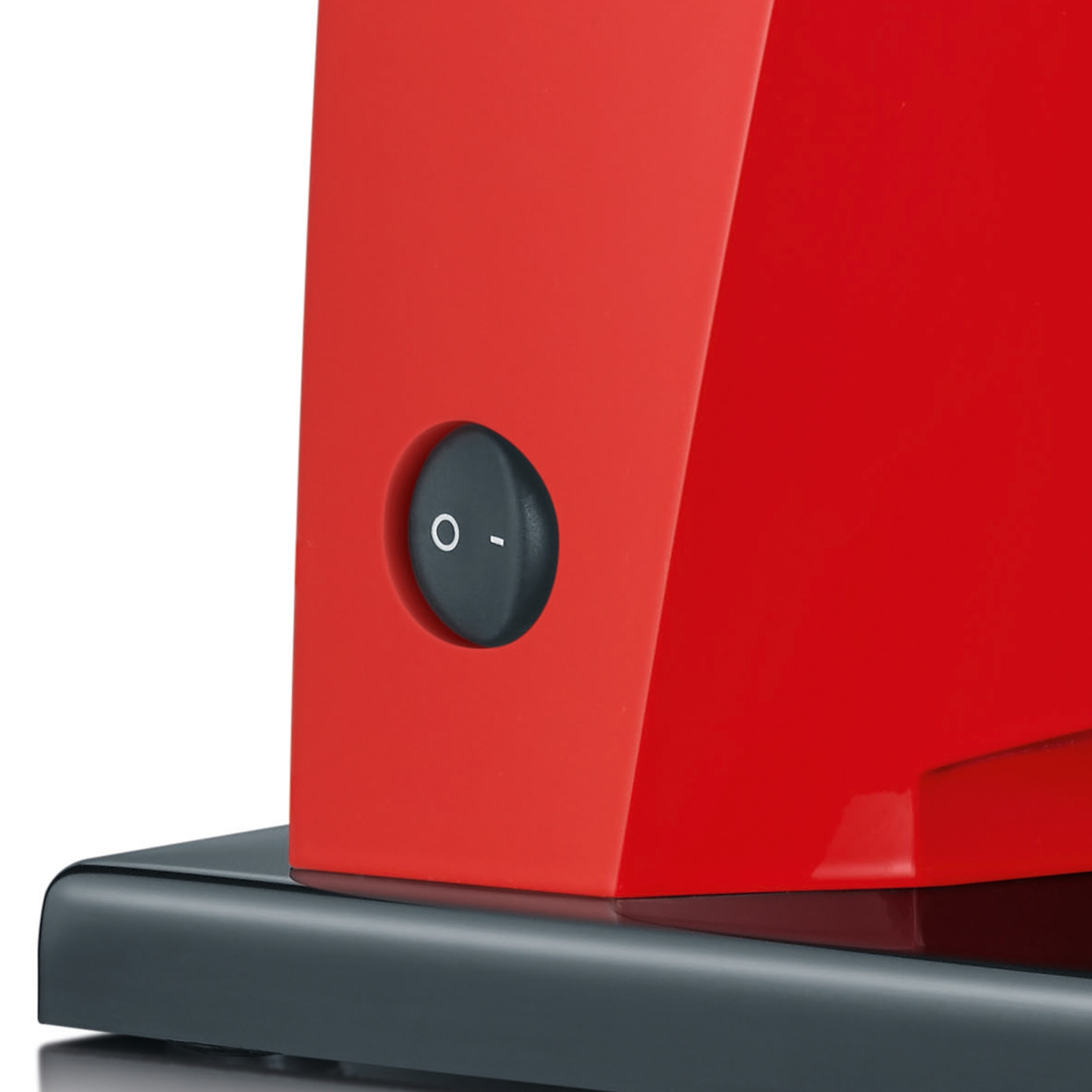 Roter Apparat mit schwarzem Knopf, der auf einer dunklen Basis steht.