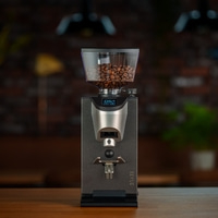 Coffee grinder with bean hopper on wooden table, digital display screen