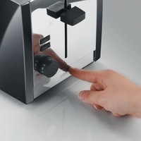 Hand drückt auf einen Toaster-Knopf, um Toast zu machen. Nahaufnahme.