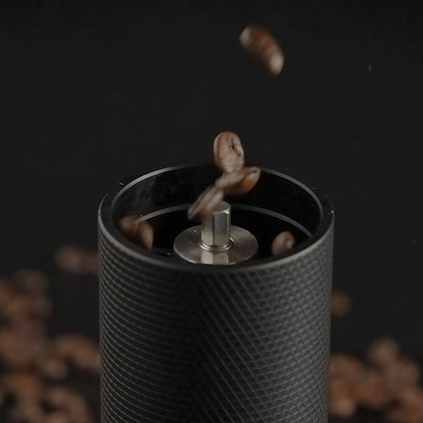 Coffee beans falling into a coffee grinder, close-up shot.