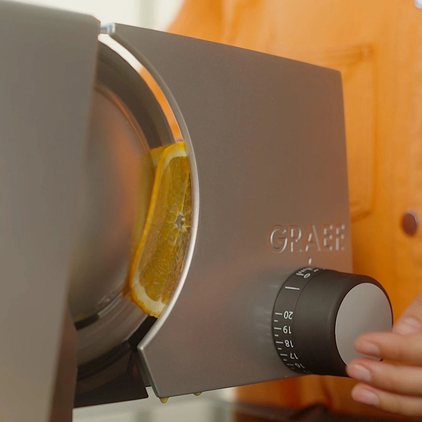 A slice of orange being cut by a Graef slicing machine.