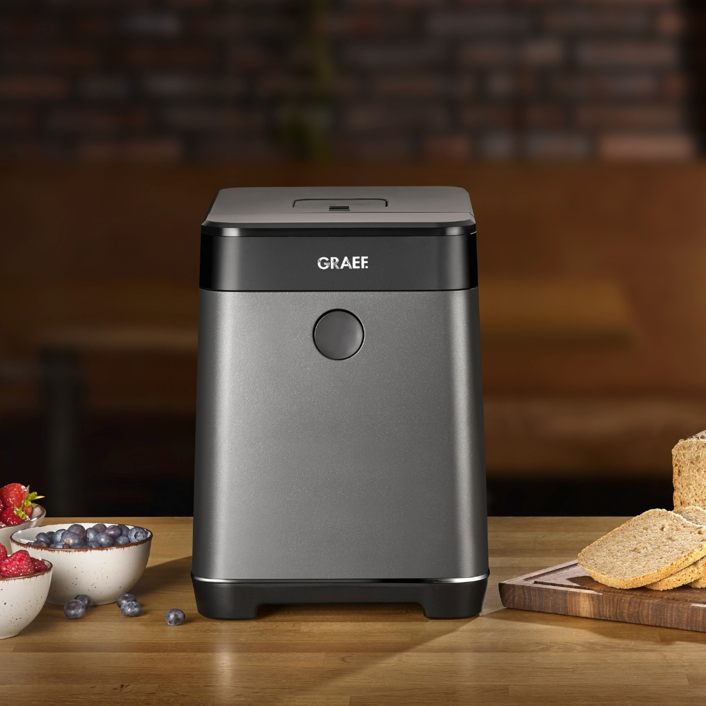 Gray kitchen appliance with fruit and bread on a wooden table.