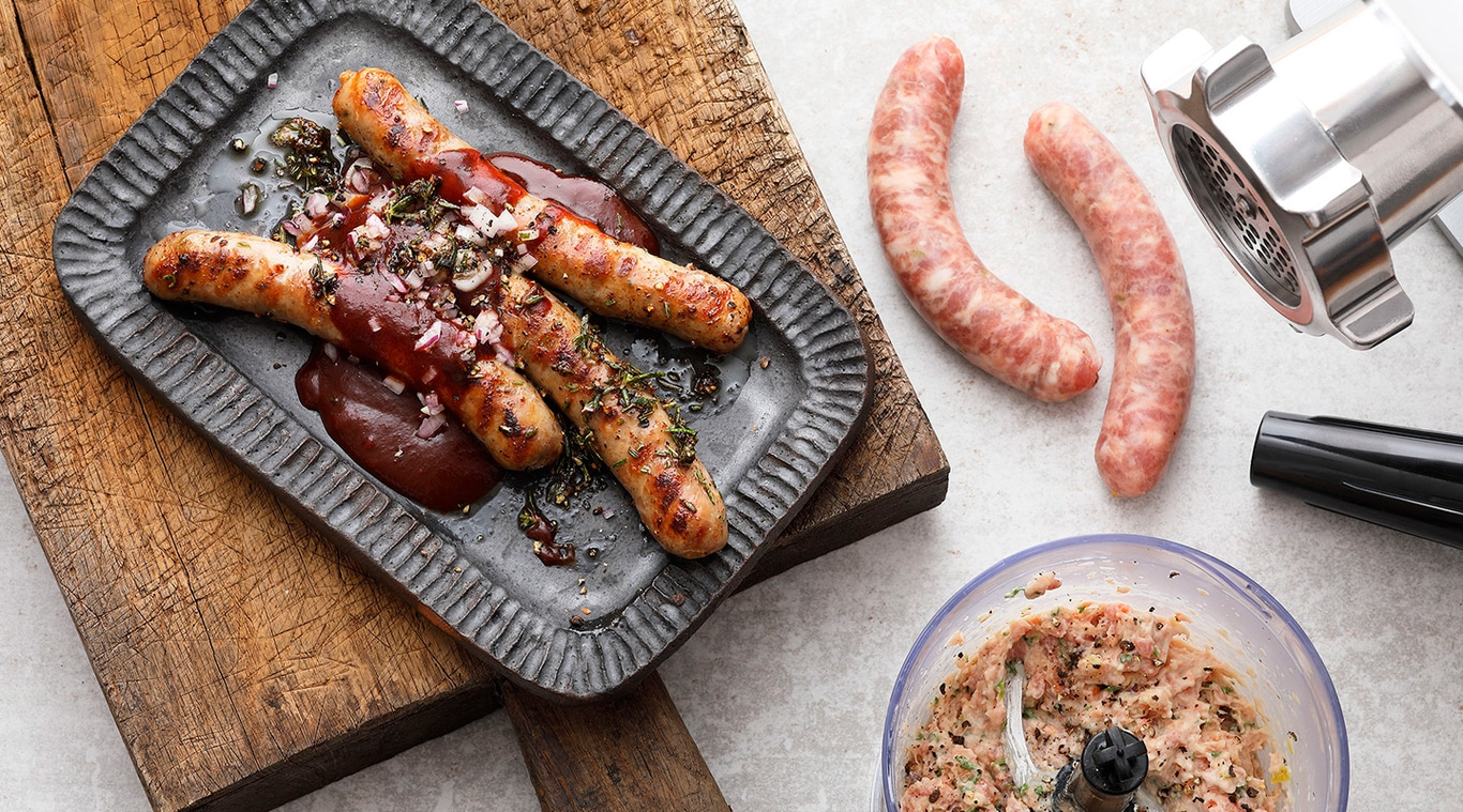Gebratene Würstchen auf einem Teller mit Sauce und Zutaten, Nahaufnahme.