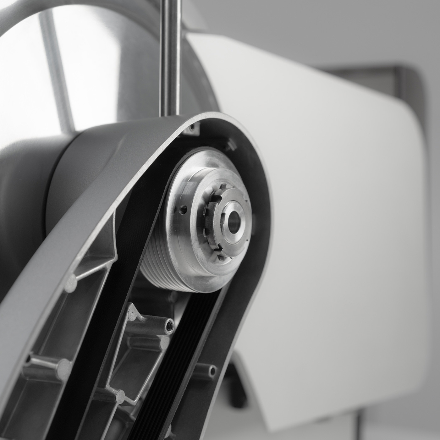 Nahaufnahme eines mechanischen Geräts mit Riemen und Zahnrädern, grau