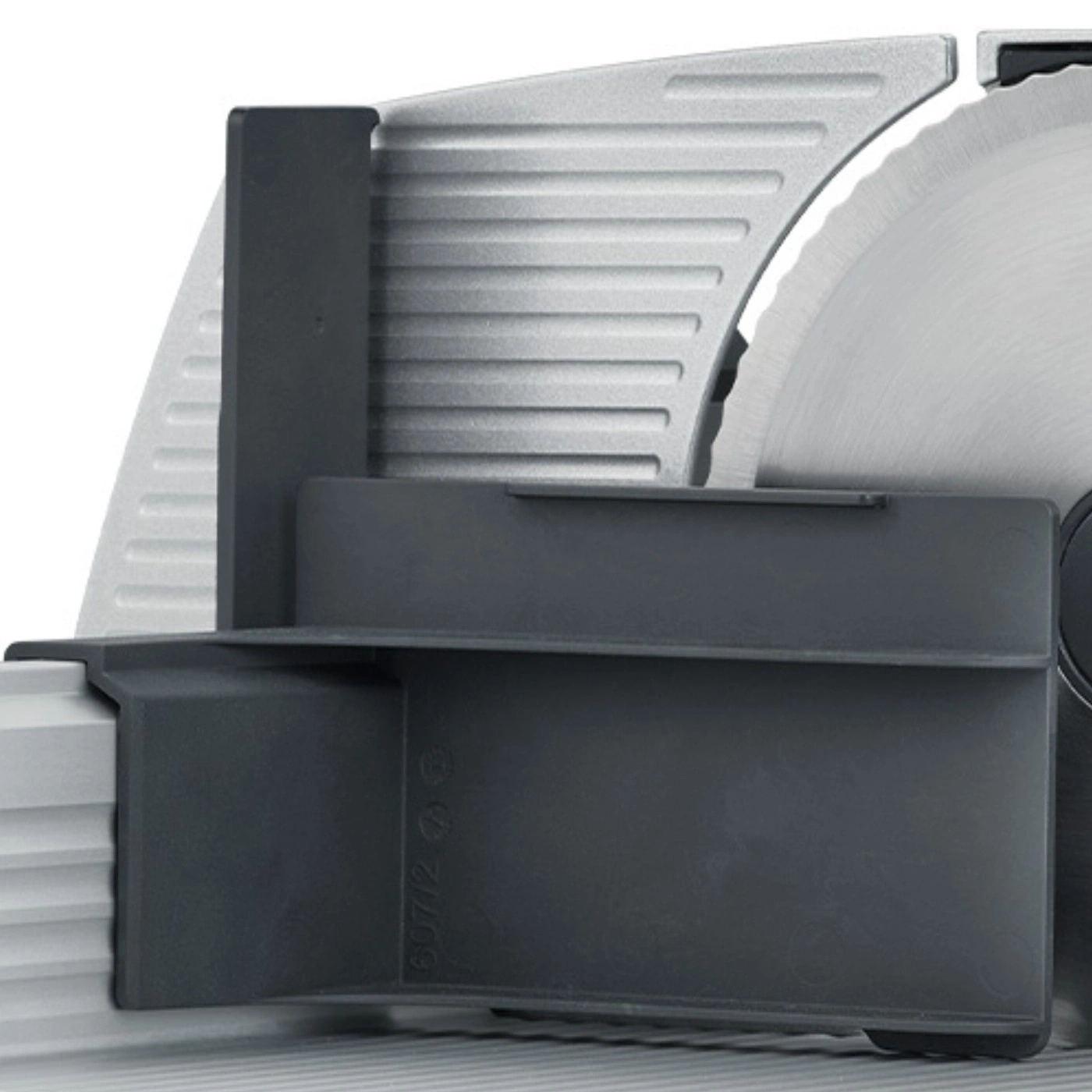 Close-up of a gray meat slicer with a black guard and a circular blade