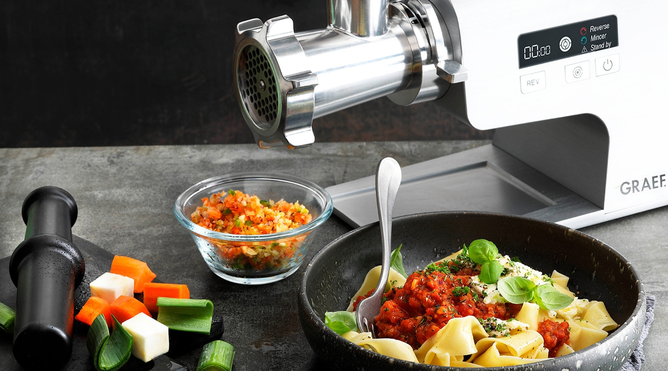 Fleischwolf mit Gemüse und Pasta. Kochen und Zubereiten von Speisen.