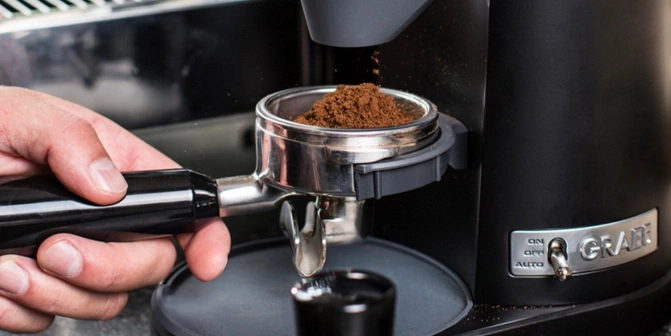 Coffee machine with freshly ground coffee falling into the filter holder.