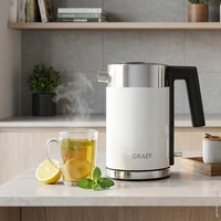 Eine Teekanne mit dampfendem Tee, Zitrone und Minze auf einer Arbeitsplatte.