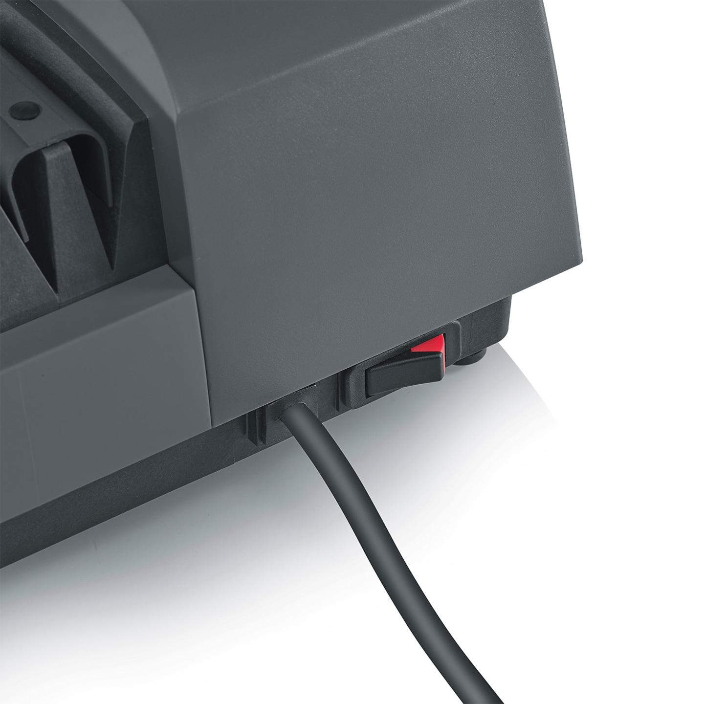 Close-up of a gray device with a red switch and black cable, detailed shot