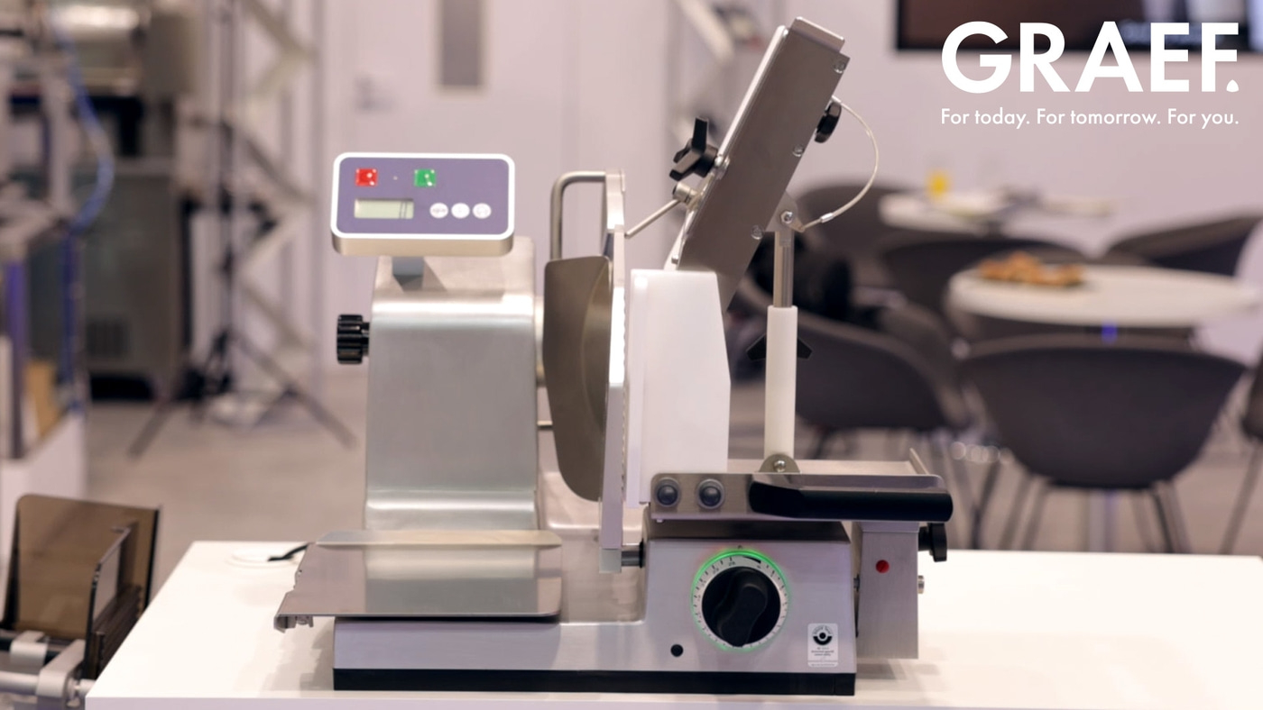 A Graef meat slicer on a table, ready to slice meat for food preparation.