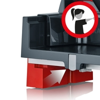 Roter Sockel mit Pfeil und Warnschild. Graues Gerät. Frau zeigt weg.