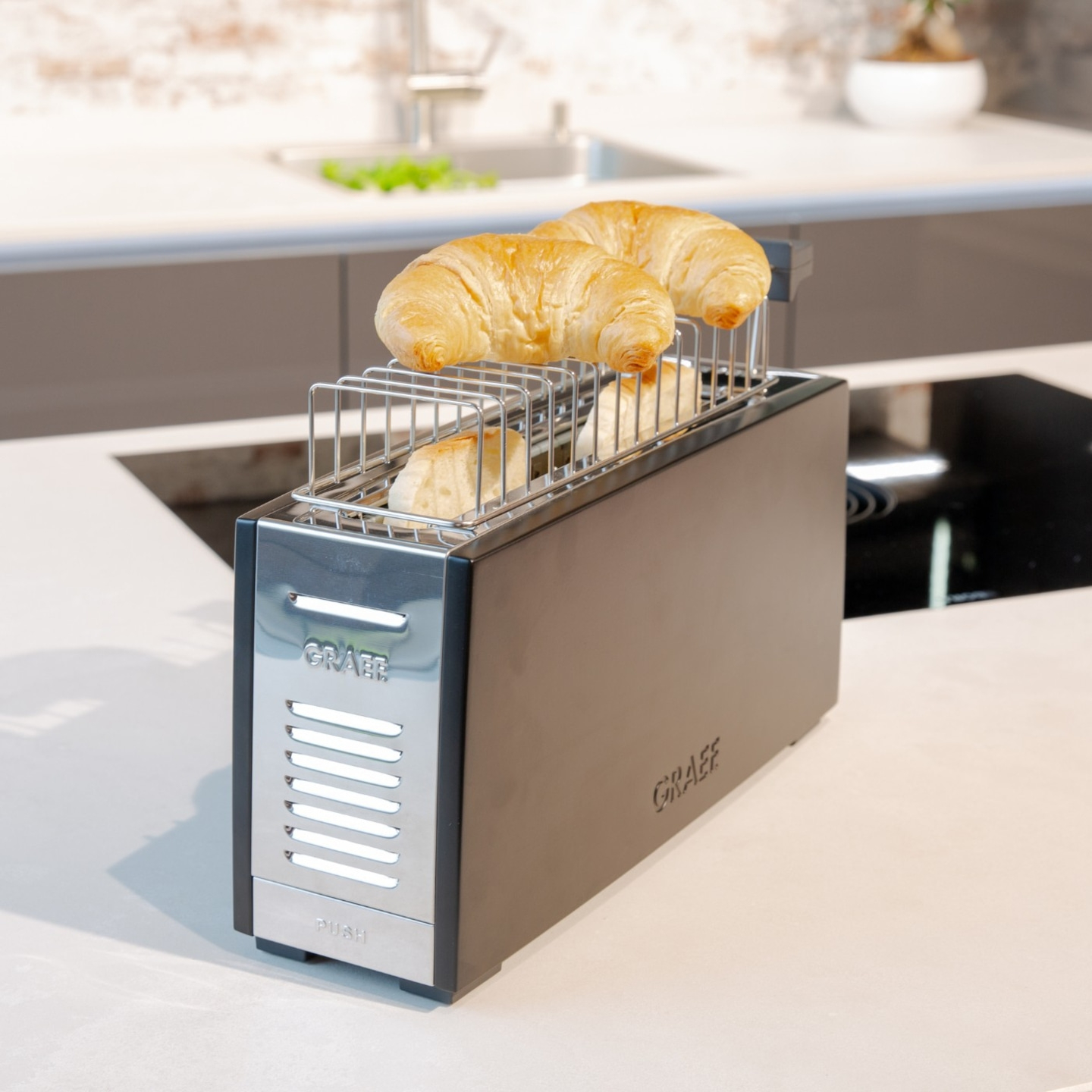 Ein Toaster mit Croissants. Küche. Frühstück. Brot. Gerät. Essen. Backen. Schwarz.