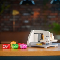 Spielzeug-Lebensmittel-Schneider mit Spielzeug-Lebensmitteln auf einem Holztisch