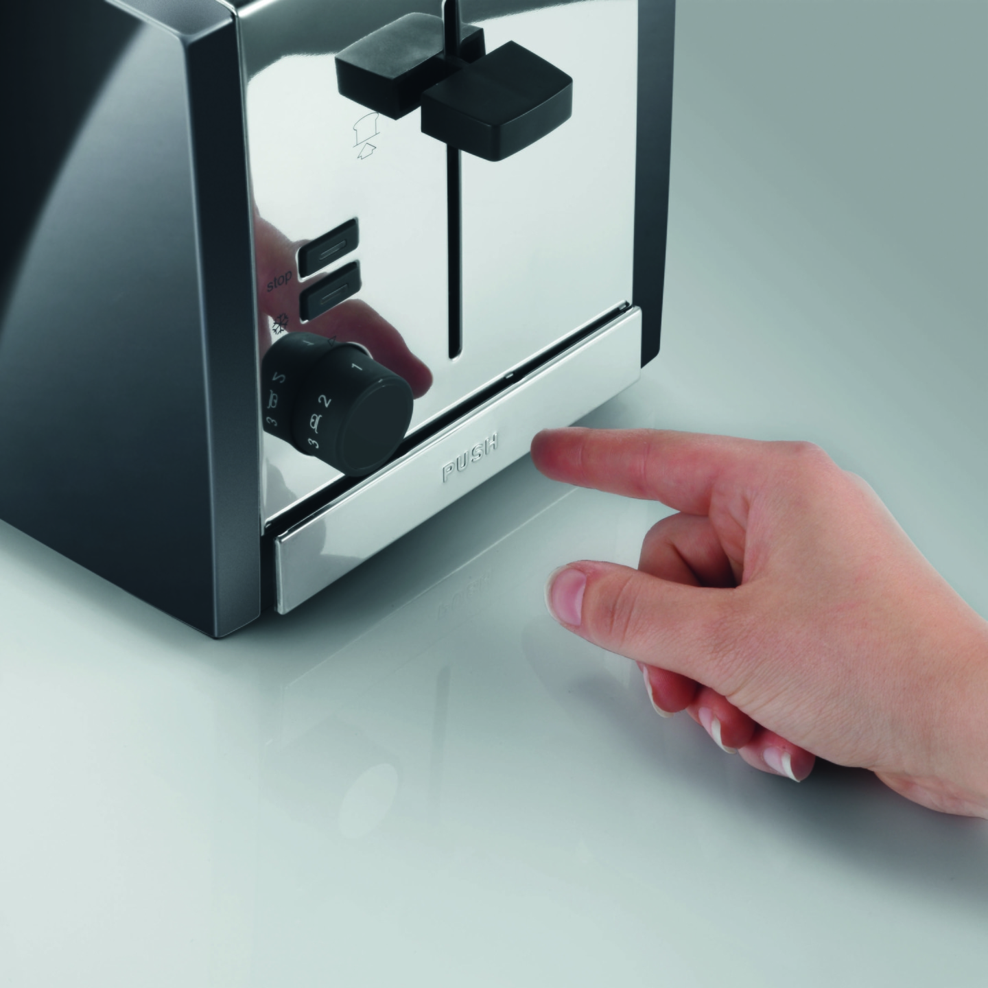 Nahaufnahme eines Toasters mit einer Hand, die auf die Taste drückt.