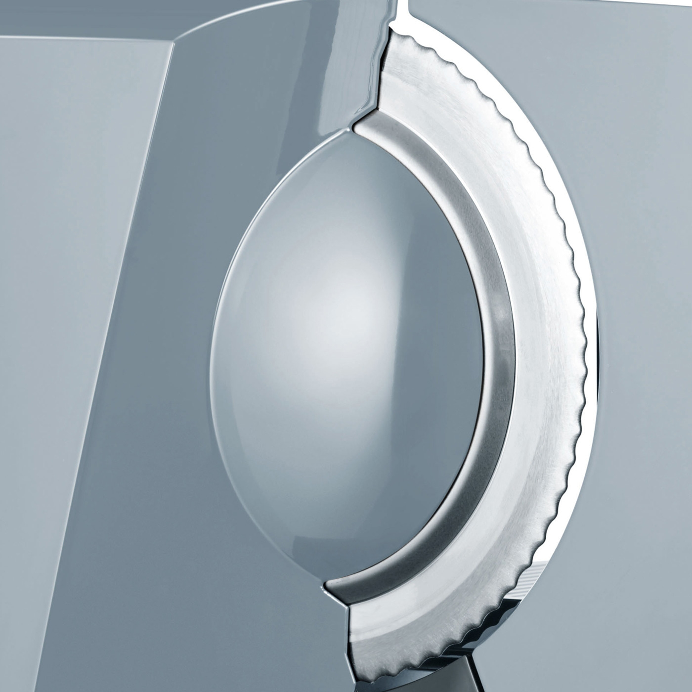 Close-up of a silver serrated blade embedded in a grey surface, with a reflective dome.